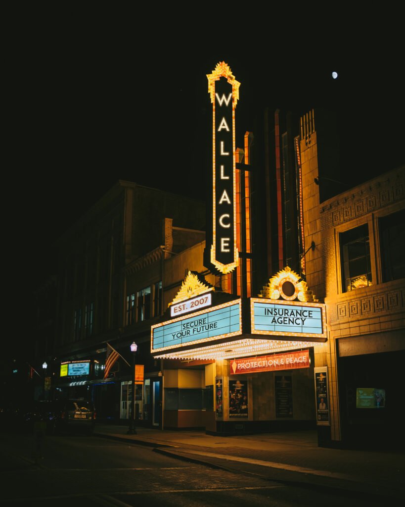 Theater neon sign at night saying Wallace Insurance Agency